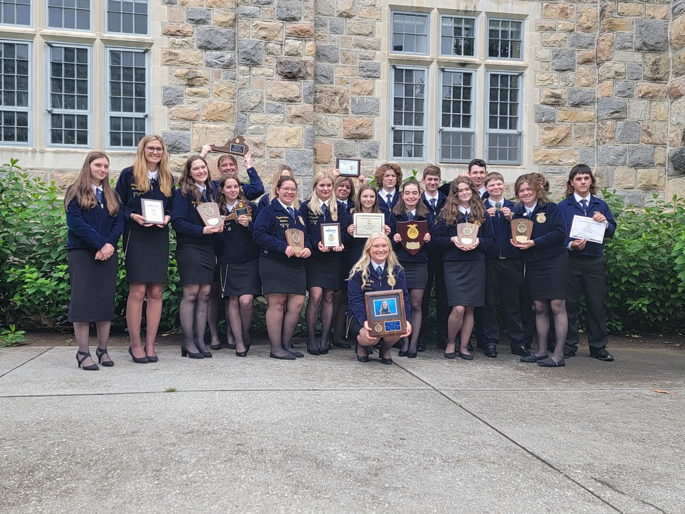 group of students wearing FFA suits holding plaques and awards