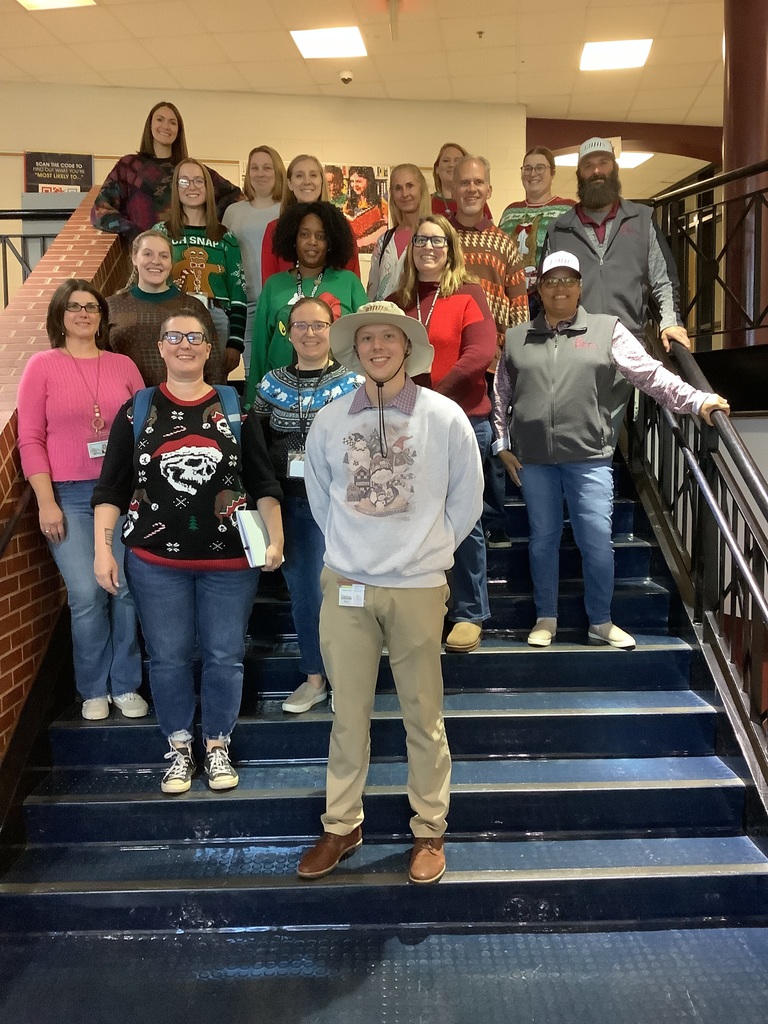 A picture of Mr. Stiver and all the staff members who wore ugly sweaters by the stairwell