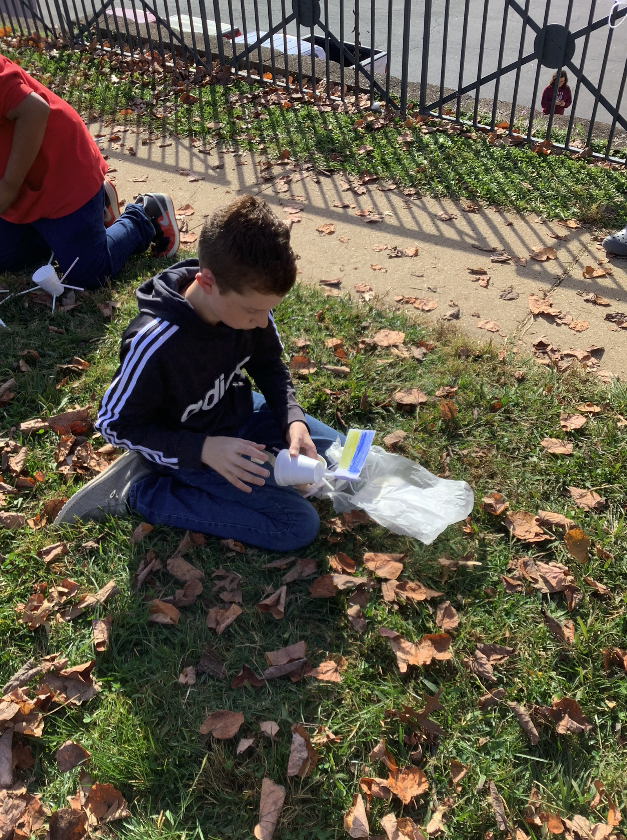a picture of a student placing an egg inside the egg drop parachute