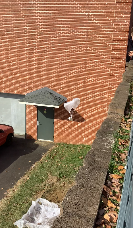 A picture of the egg drop parachute mid flight over a railing