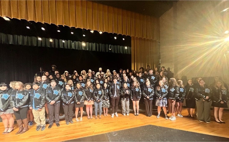 students on stage in letter jackets
