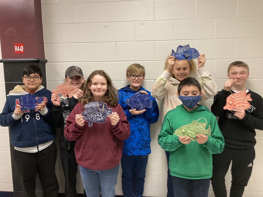 A picture of a bunch of students holding up their clay fish creations