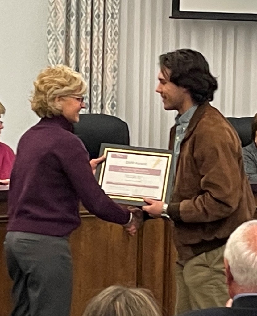 student receives an award from Board Member