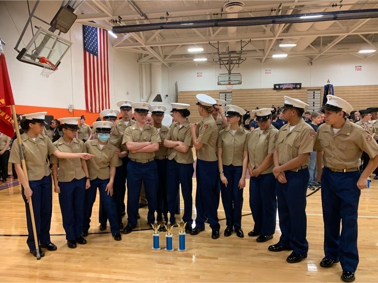 cadets standing in a gymnasium with three trophies