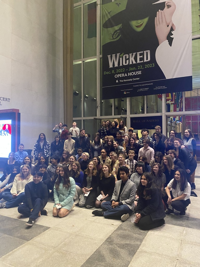 A picture of the whole Theatre Department in front of a sign for Wicked the musical. 