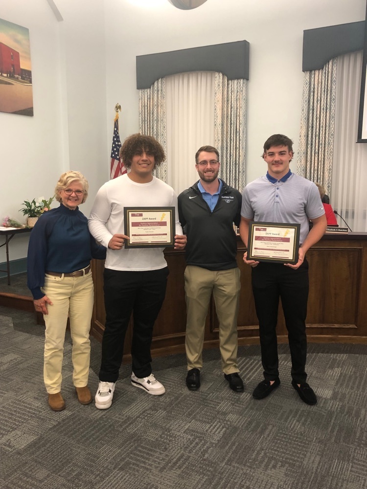 4 people standing in a room two boys holding awards