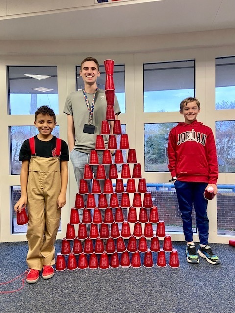 Students engineer a cup tower as tall as their teacher.