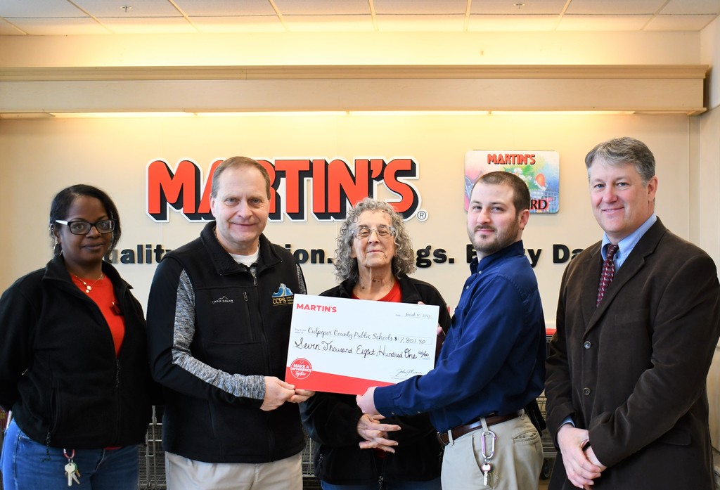 five people with large check and martins logo in the background