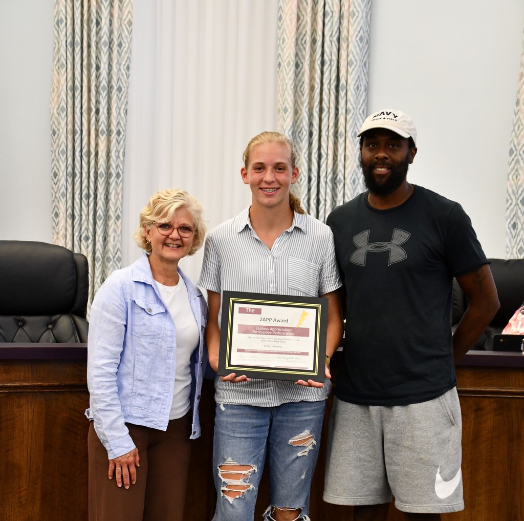 student holding award with coach and board member