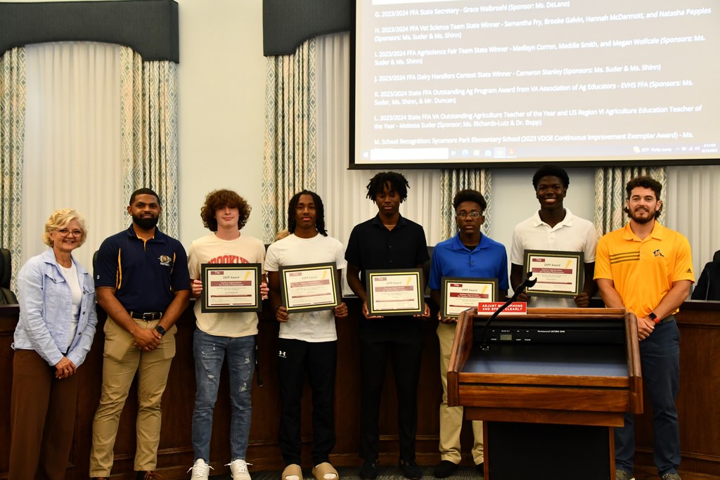students holding award with coaches and board member 