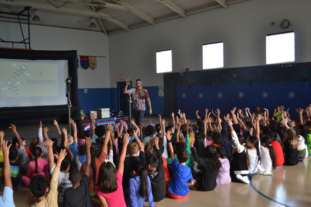 PTO fundraiser kick off assembly with students raising their hands