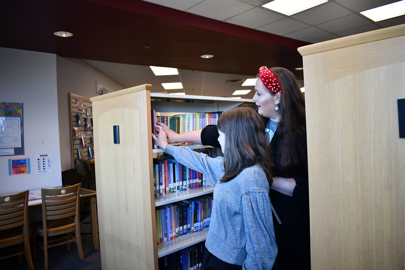 Kendall places her book on the library shelf at FTB